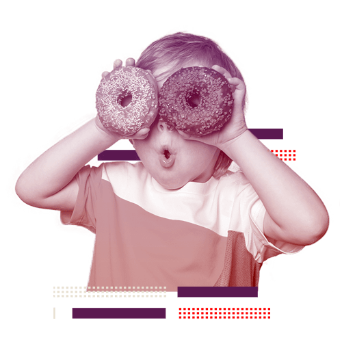 Criança segurando donuts sobre o rosto e fazendo careta.